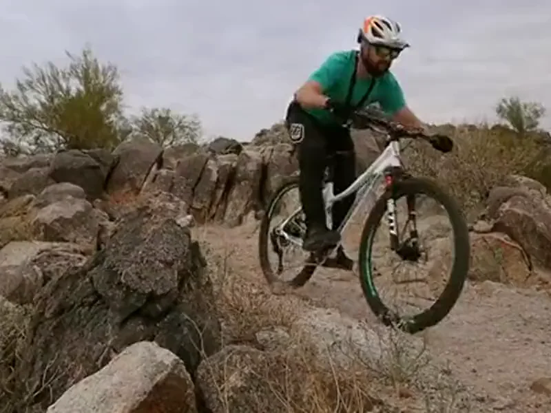 Mountain biker on a ZTZ air suspension fork rolling down a rocky desert ledge and landing on the trail below